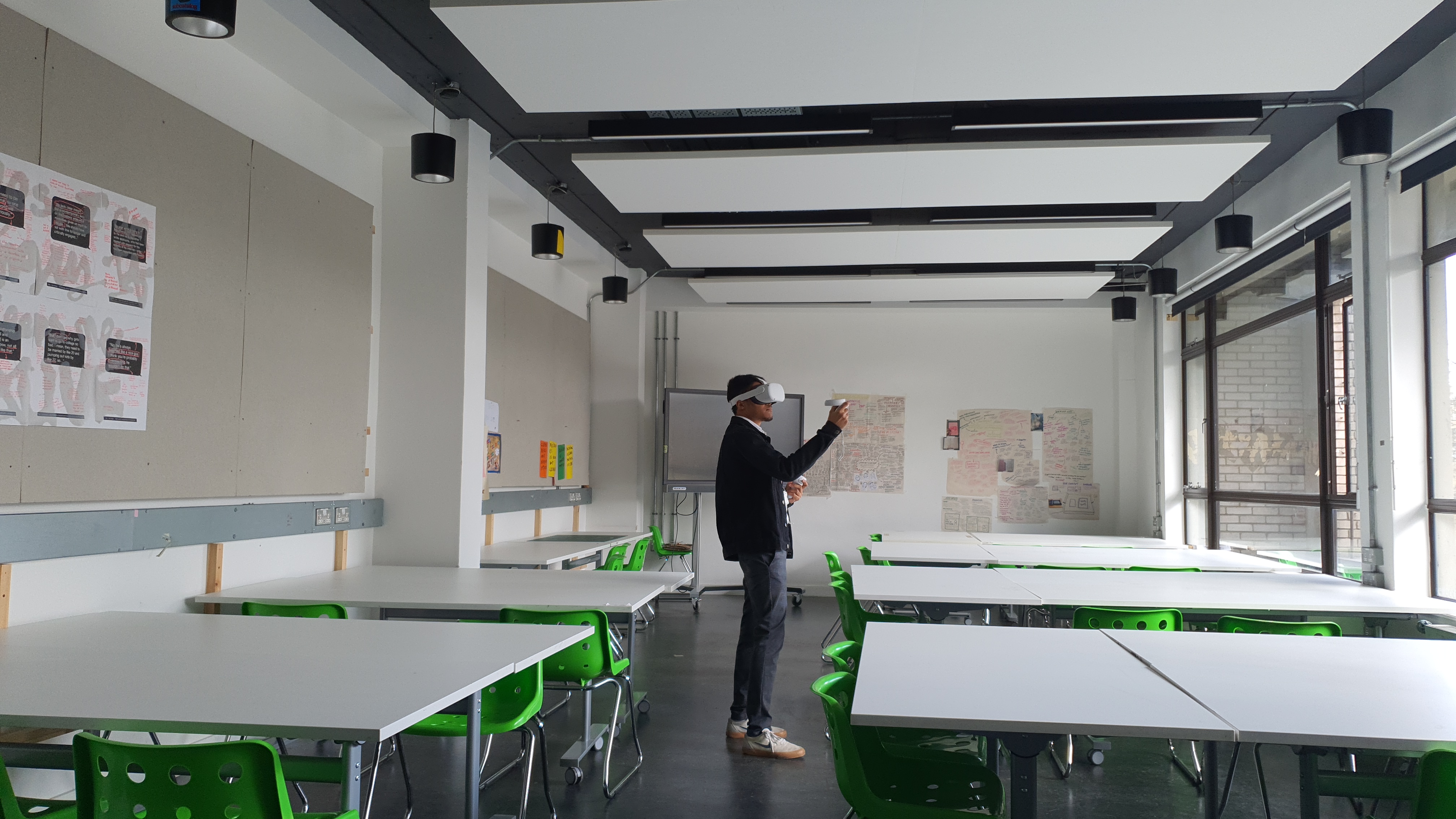 a medium sized room with tables on each side, in the middle is a guy playing VR